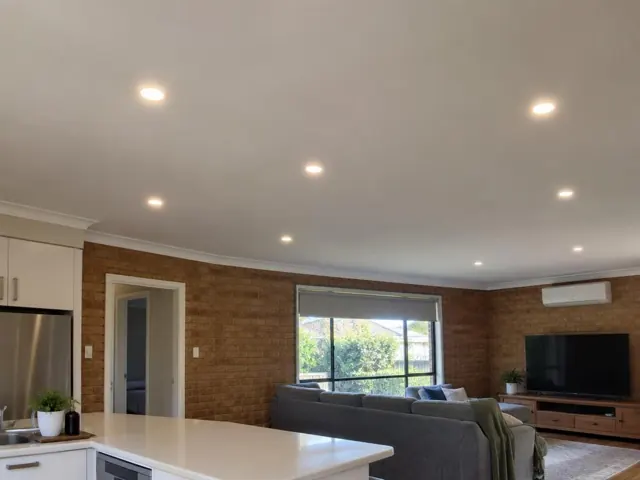 Living room with recessed ceiling downlights, brick feature wall and sofa in Aberglasslyn